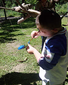 Un enfant peint un mobile en bois flotté
